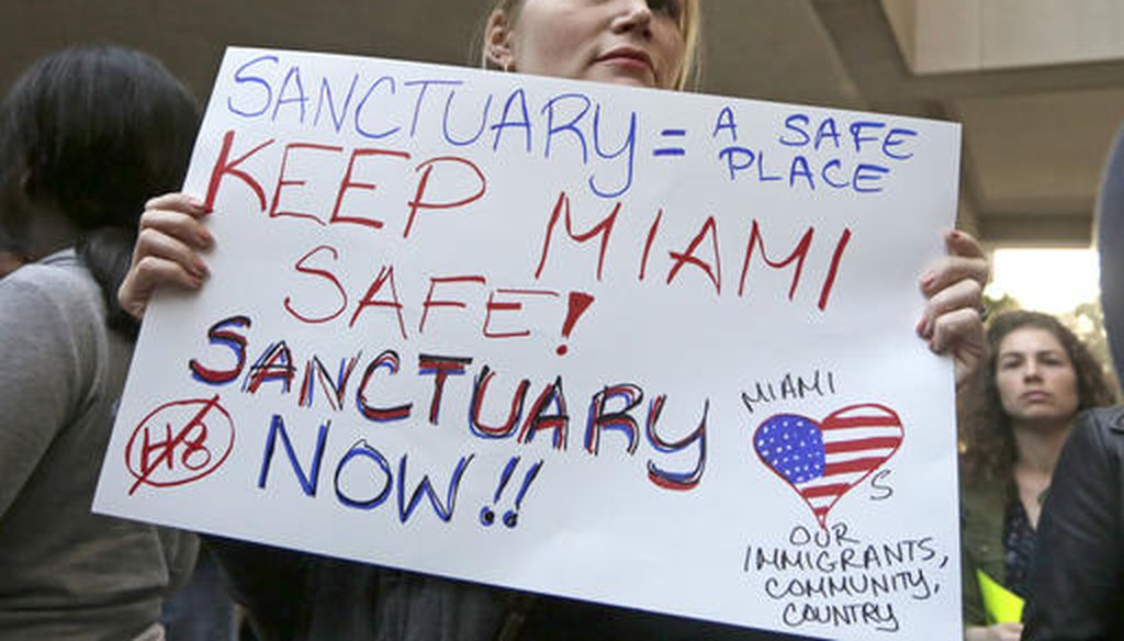 Protester Jennifer Smith-Camejo holds a sign during a rally in Miami Jan. 31, 2017. Miami-Dade County Mayor Carlos Gimenez issued a controversial order assuring the Trump administration that Miami-Dade is not functioning as a sanctuary city. (AP)
