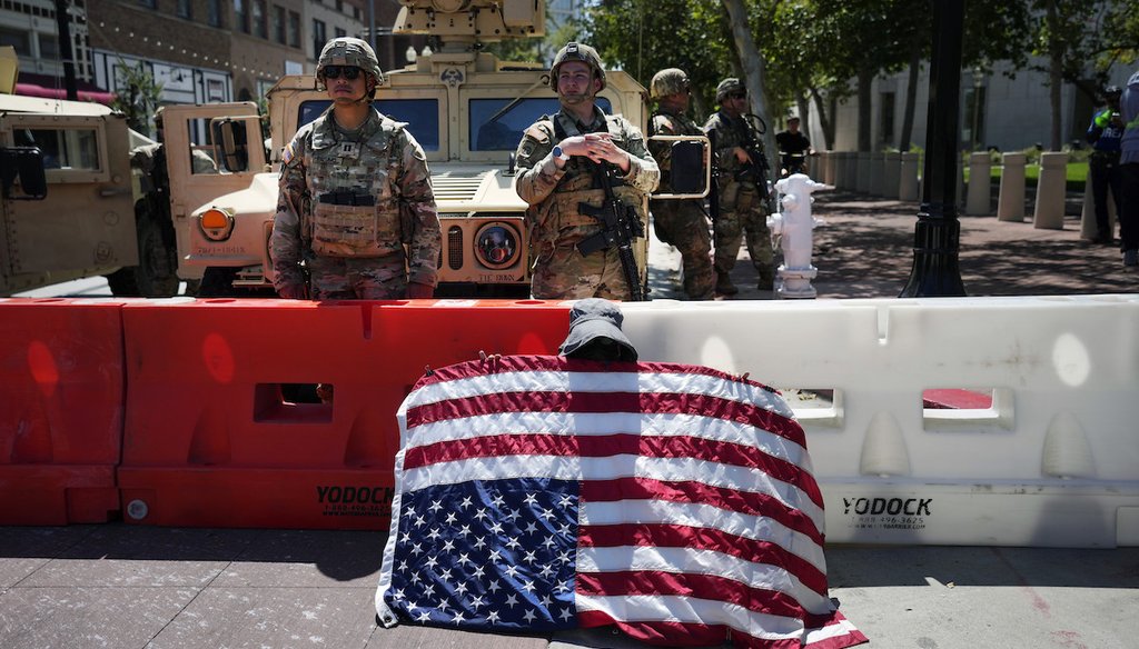 Protester Annie Jones holds a U.S. Flag upside down as a sign of distress while California National Guard stand behind a barricade in Santa Ana, Calif. on Tuesday, June 10, 2025. (AP)